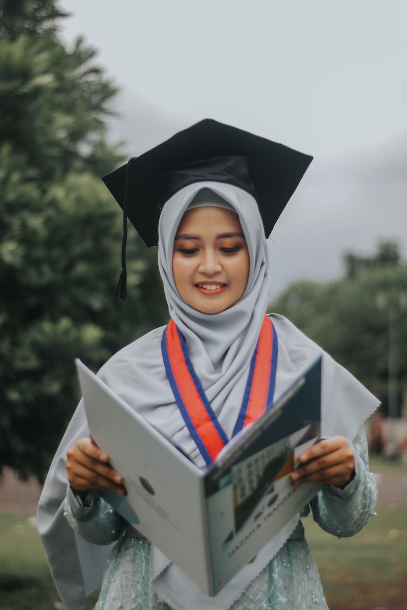 Woman in White Academic Dress Holding Book